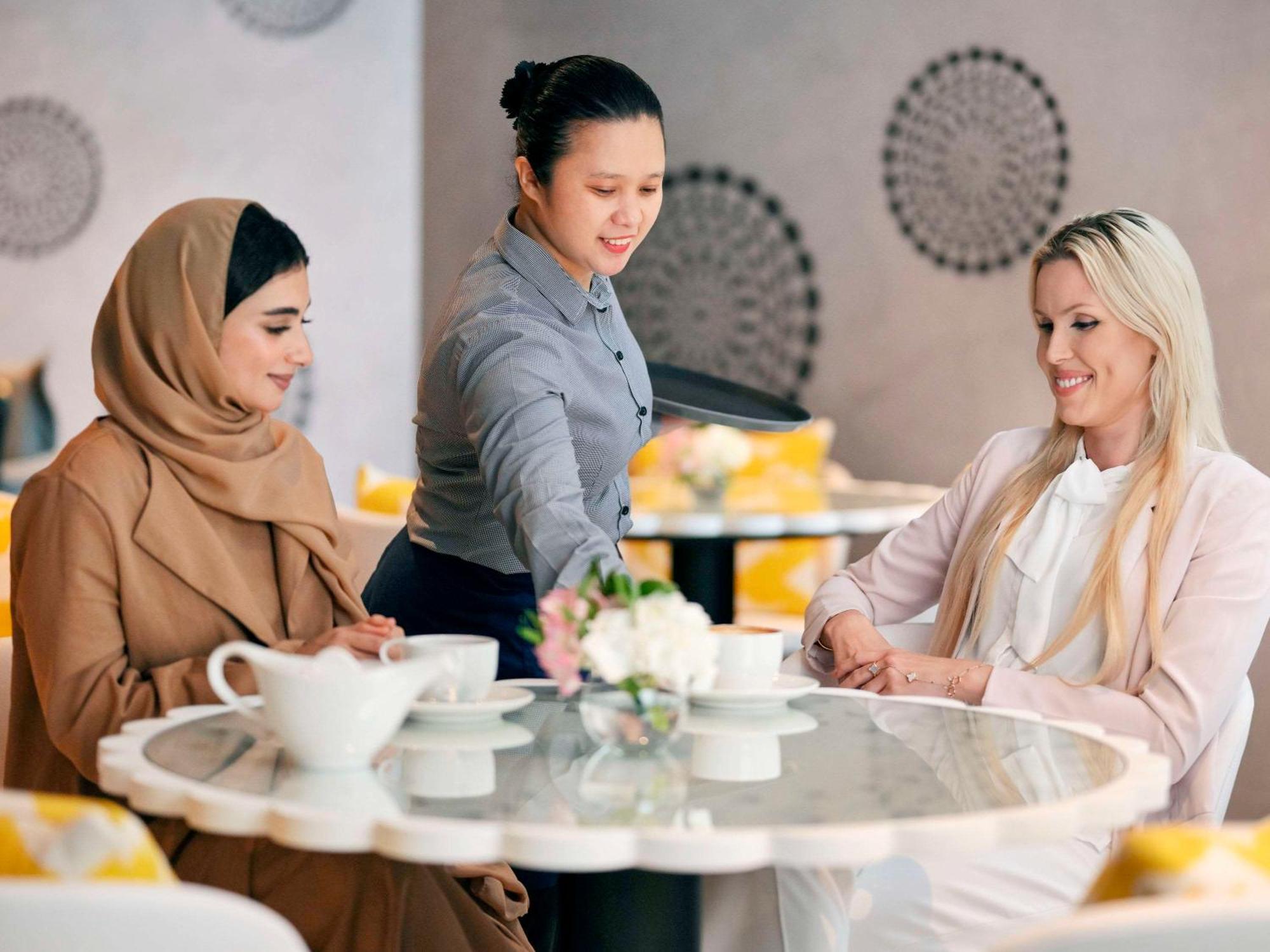 Moevenpick Hotel & Apartments Ghala Muscat Exterior photo A waitress serving customers